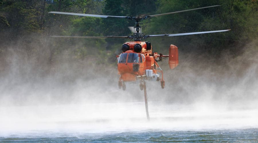 Firefighting-helicopter-is-hovering-over-body-of-water-to-refills-water-tanks Firefighting-helicopter-is-hovering-over-body-of-water-to-refills-water-tanks