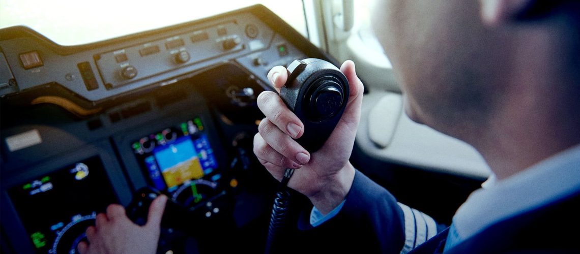 A pilot speaking into a push to talk radio in an airplane